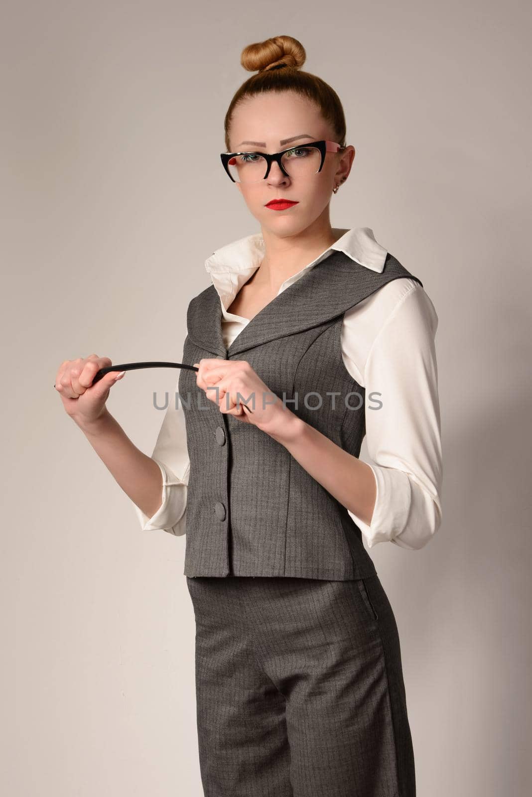 slim serious young woman teacher in suit bends pointer in hands by zartarn