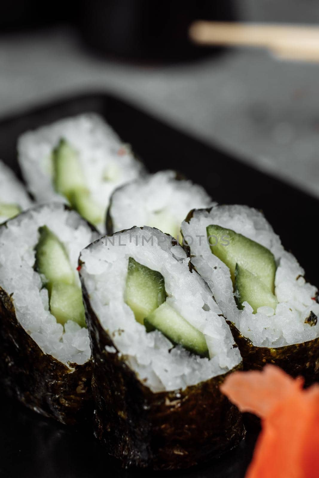 Delicious, juicy and mouth-watering maki with cucumber. Sushi on a gray background by UcheaD