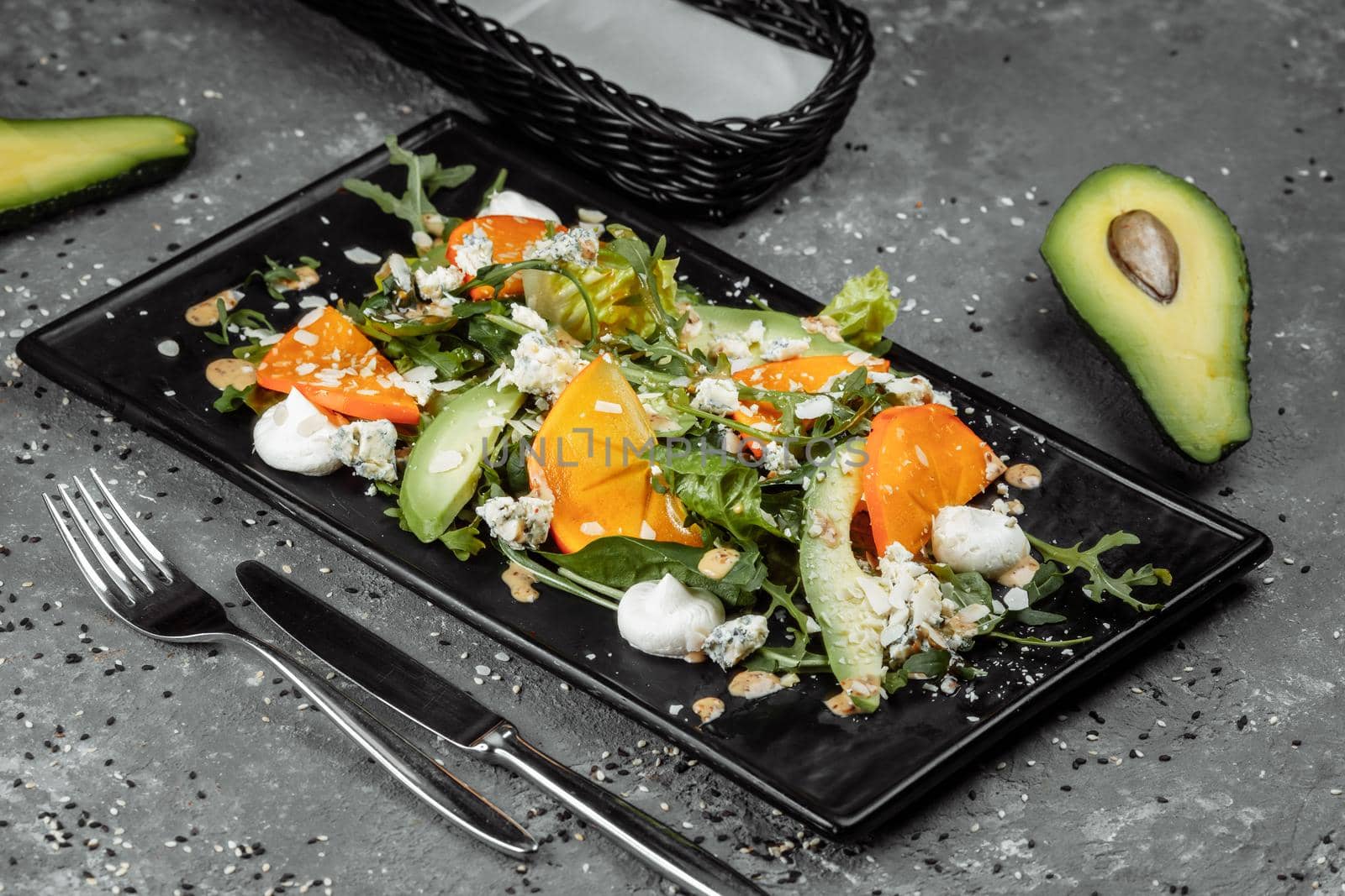 Fresh salad with fruits and greens on dark canvas background. Healthy food.