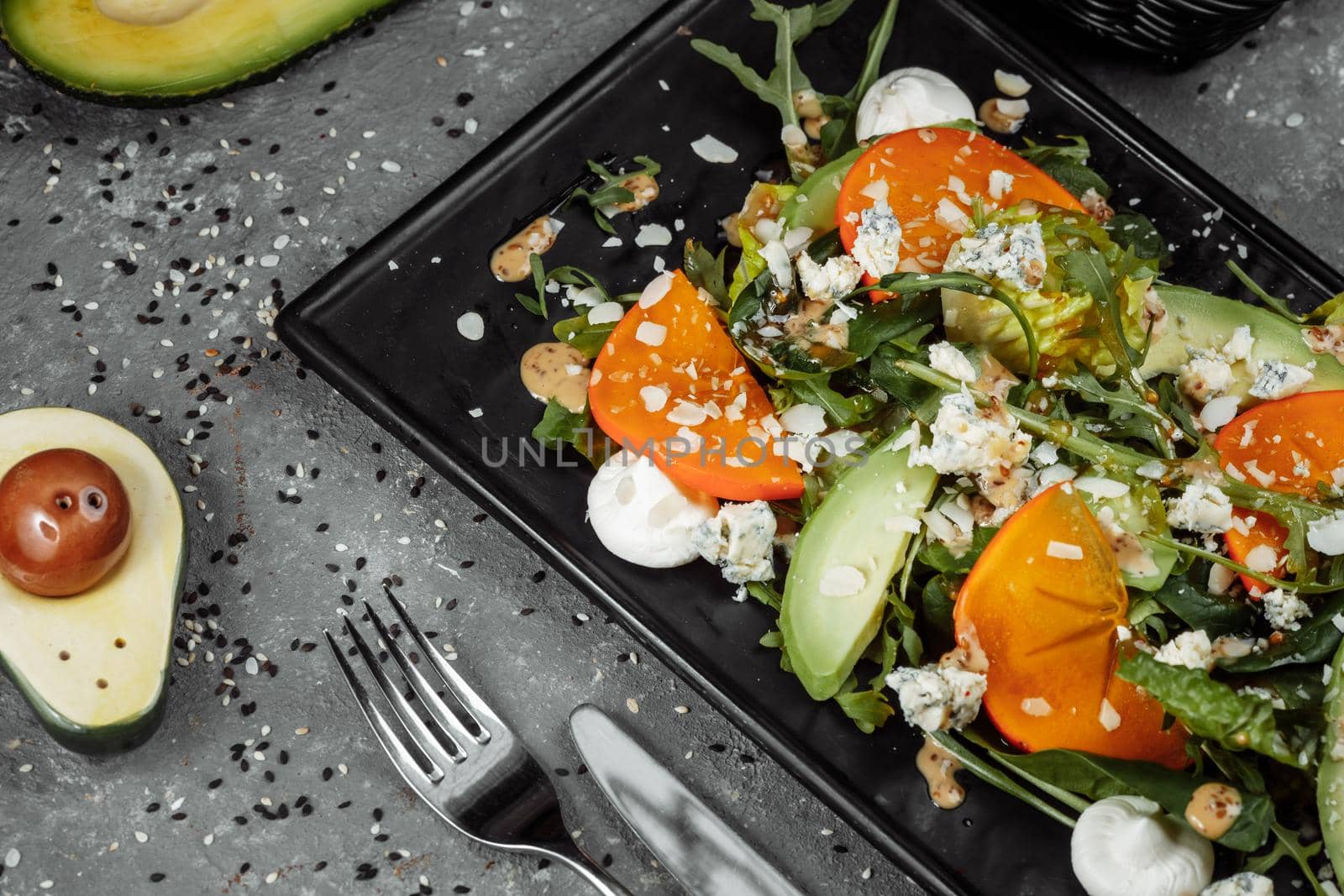 Fresh salad with fruits and greens on dark canvas background. Healthy food.