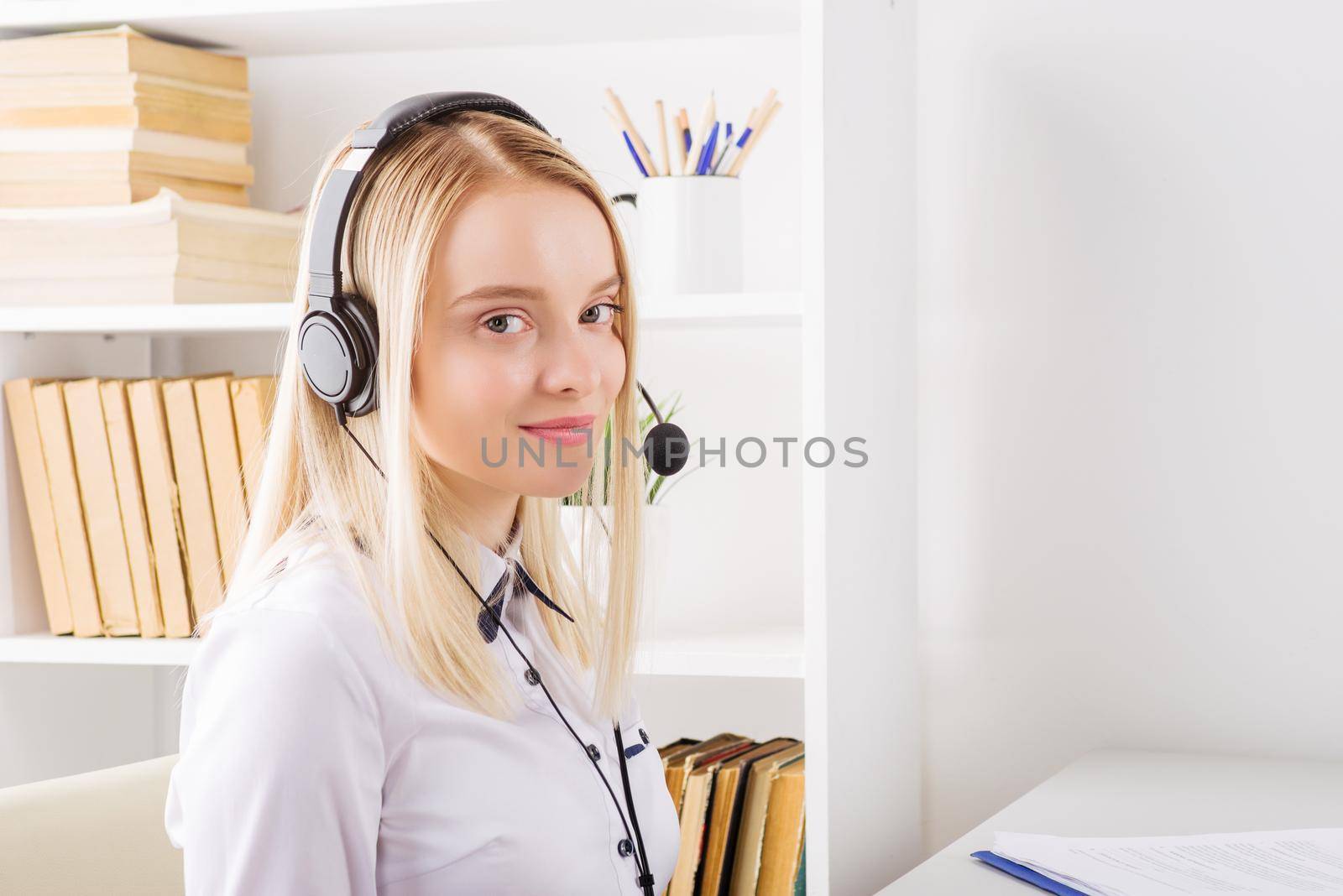 Portrait of happy smiling female customer support phone operator at workplace. - Image