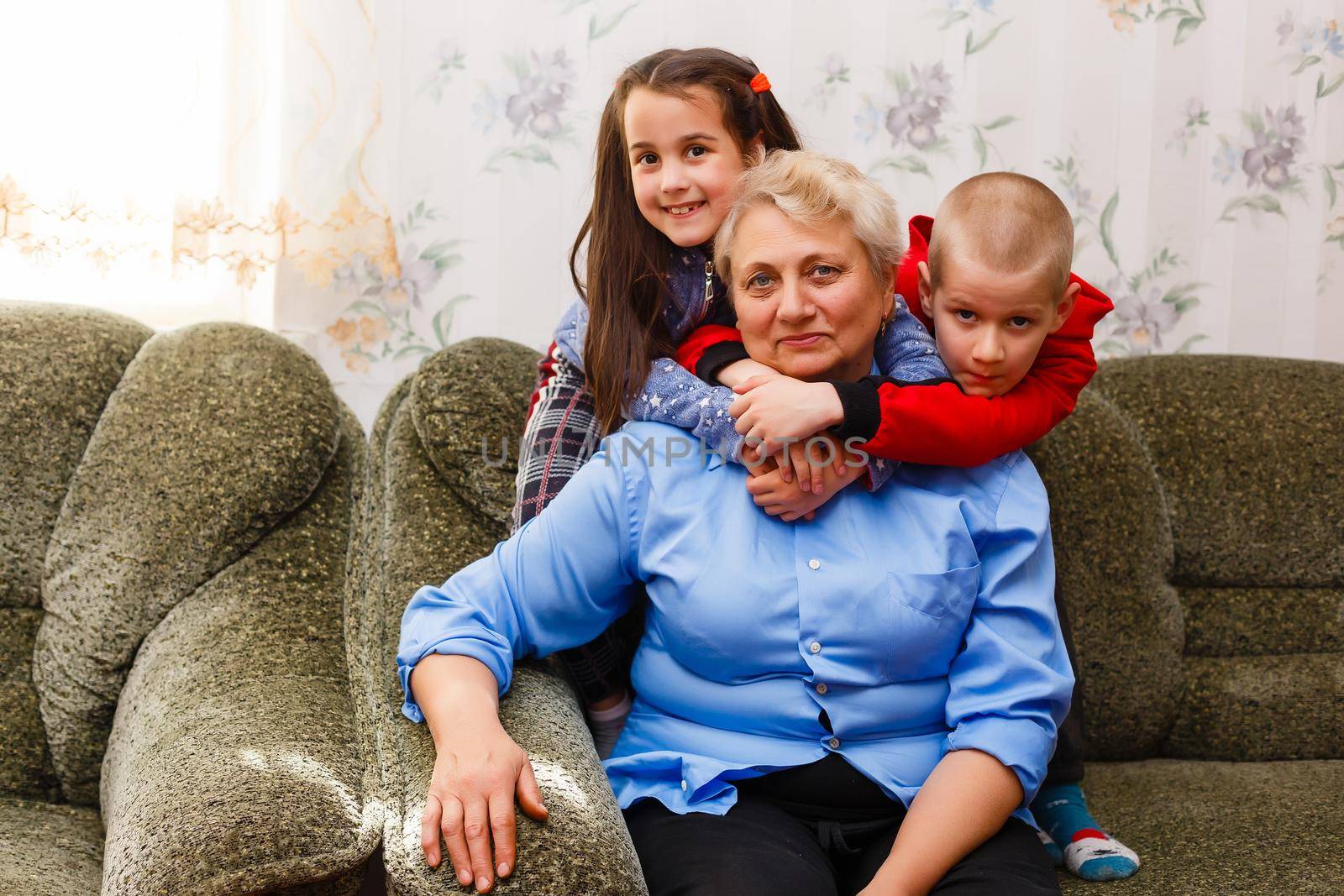 Grown up adult smiling grandchildren embraces elderly grandmother glad to see missing her, visit of loving relatives enjoy communication, cuddle as symbol of connection, love and support concept