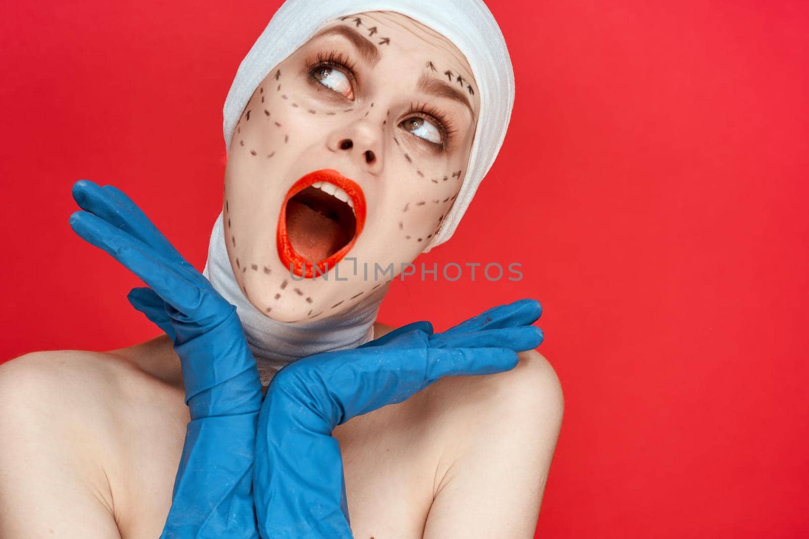 woman posing in blue gloves red lips surgery facial rejuvenation red background. High quality photo
