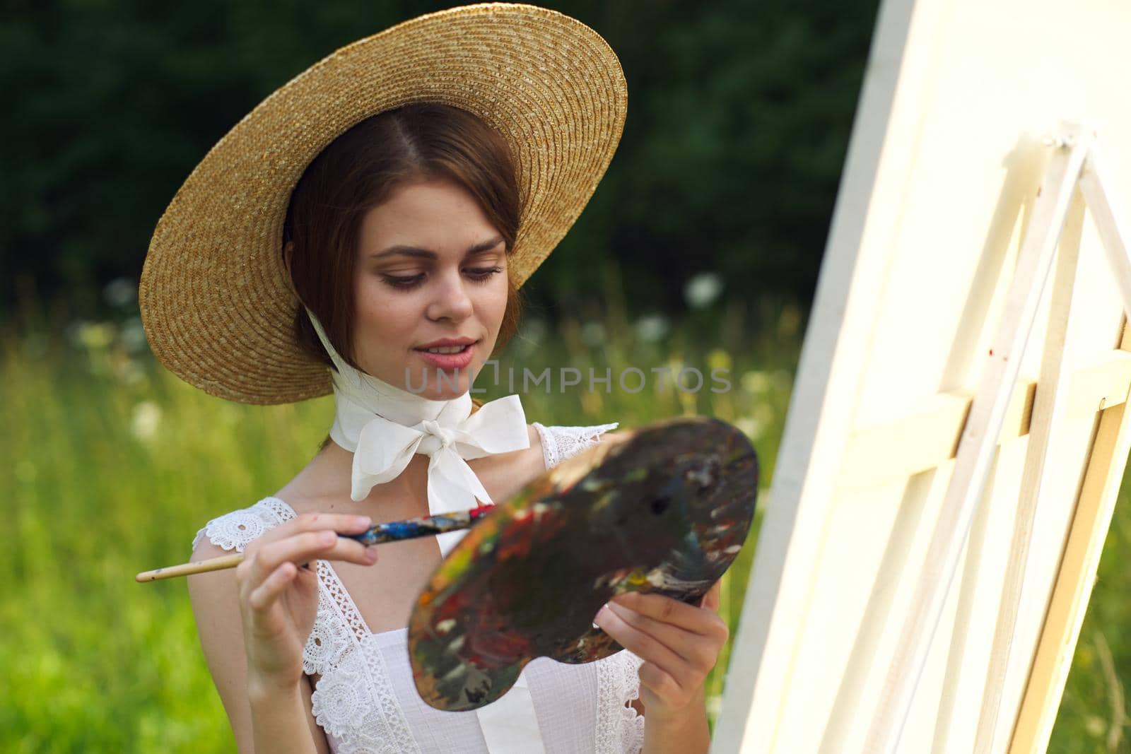 Woman in white dress artist paints on nature palette creative. High quality photo