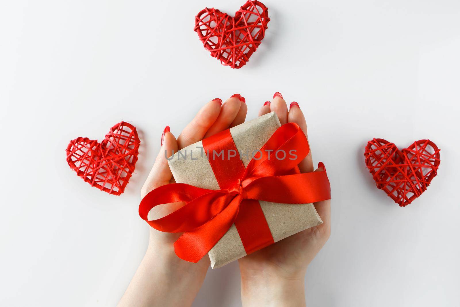 Gift with a red ribbon in hands on a white background by Statuska