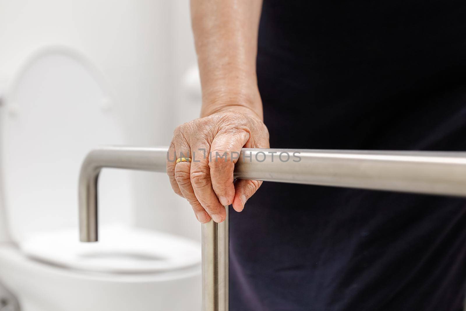 Elderly woman holding on handrail in bathroom. by toa55