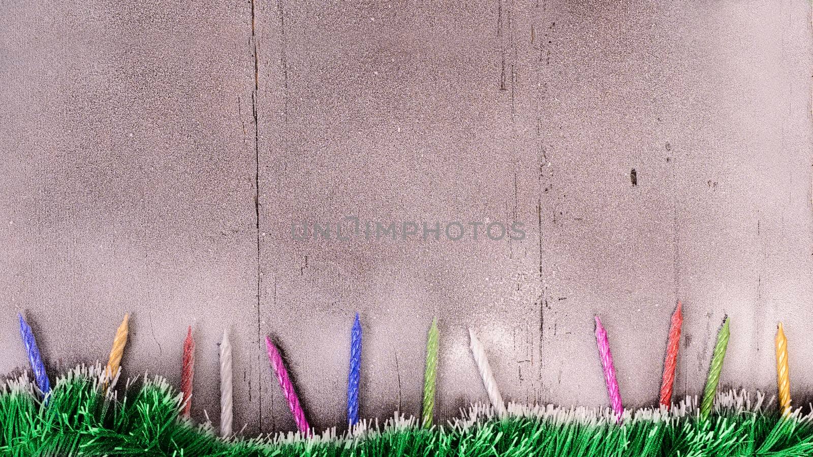 Christmas card. Tinsel and candles on a snow-covered wooden background with empty spase