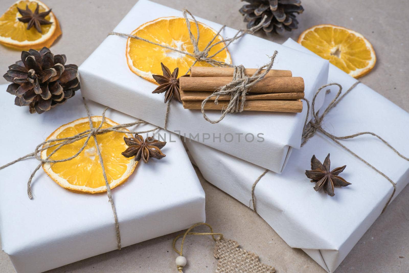 New Year composition. On beige craft paper, gift boxes, dry orange slices, pine cones, cinnamon, cloves. Cozy Christmas concept