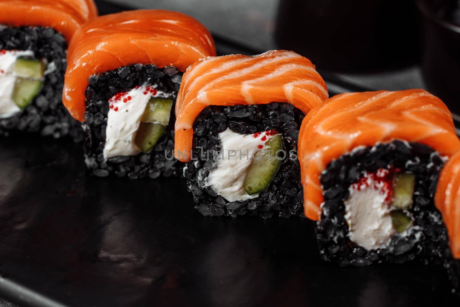 A set of sushi rolls Philadelphia with red fish, cream cheese and black rise lies in a plate boat. Sushi rolls on a gray background by UcheaD