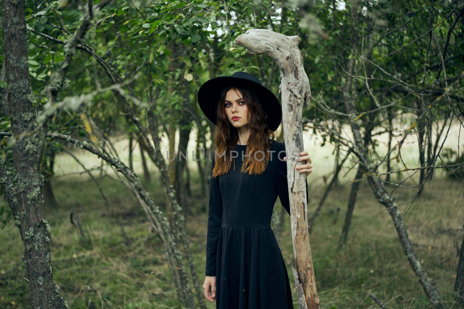 woman in witch costume in forest posing staff logic. High quality photo