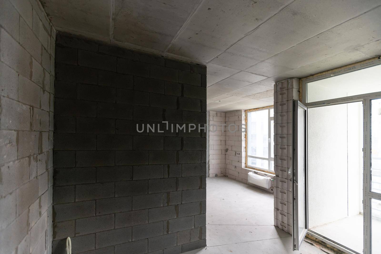 A new unfinished apartment room with the bare brick walls without decoration.