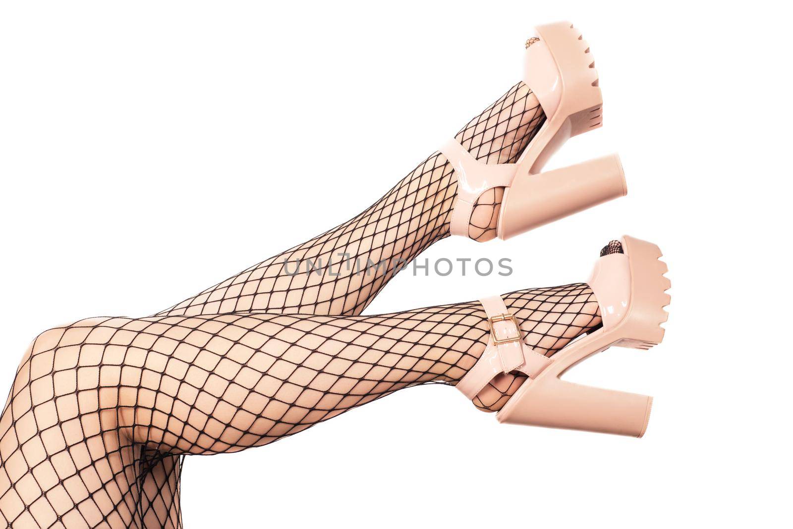 Sexy female legs in net stockings and sandals with high heels isolated over white.
