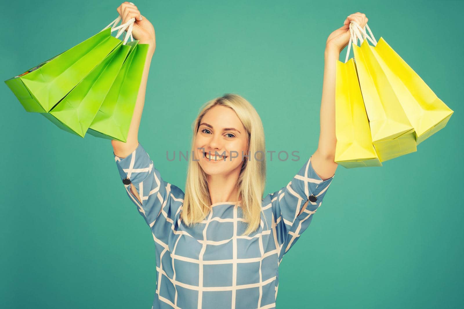 Happy girl in a checkered blouse holds shopping bags on blue background. toned