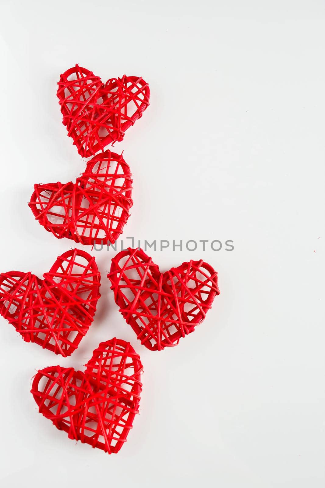 Red handmade hearts made of twigs on a white background. A lot of red hearts from twigs of vines on a white background. Background from heart for design for Valentine's day, place for text., vertical orientation