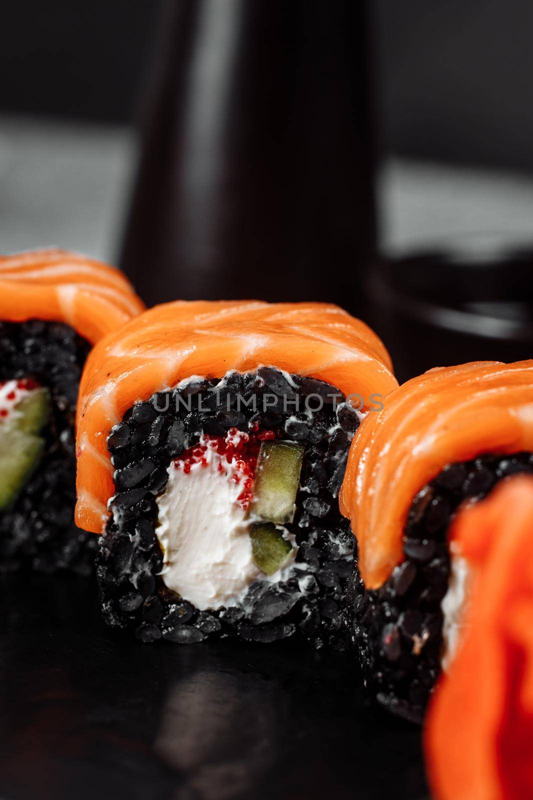 A set of sushi rolls Philadelphia with red fish, cream cheese and black rise lies in a plate boat. Sushi rolls on a gray background.