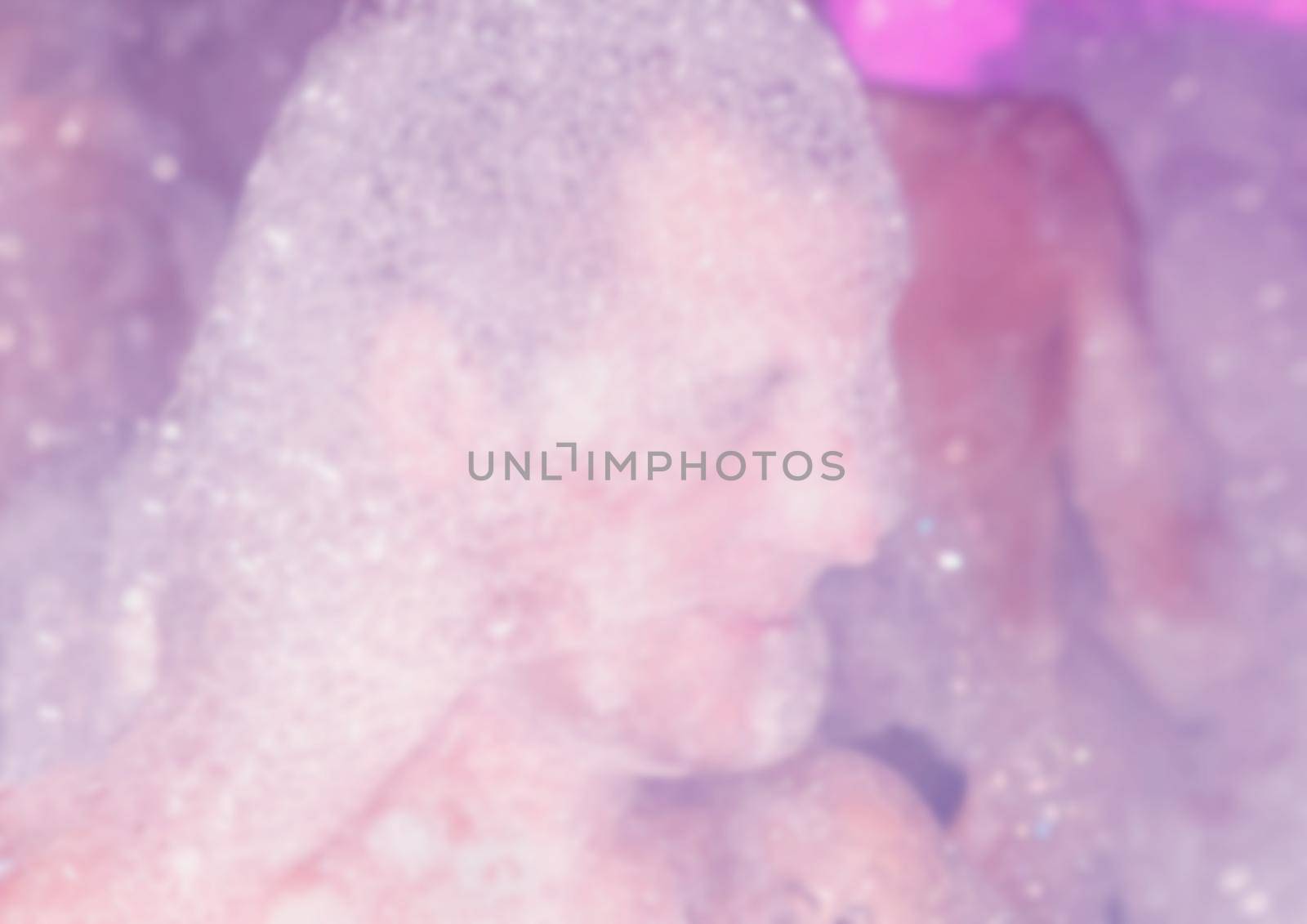 Head and face of a guy in soapy foam with bubbles at a foam party, close-up, blurred.