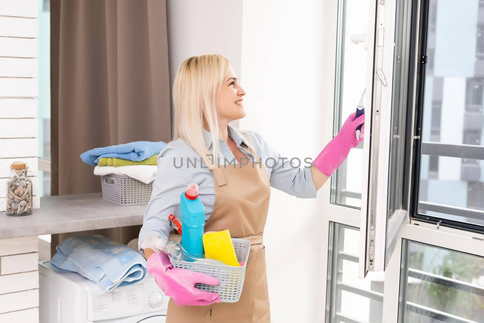 Smiling black woman cleaning windows with glass cleaner