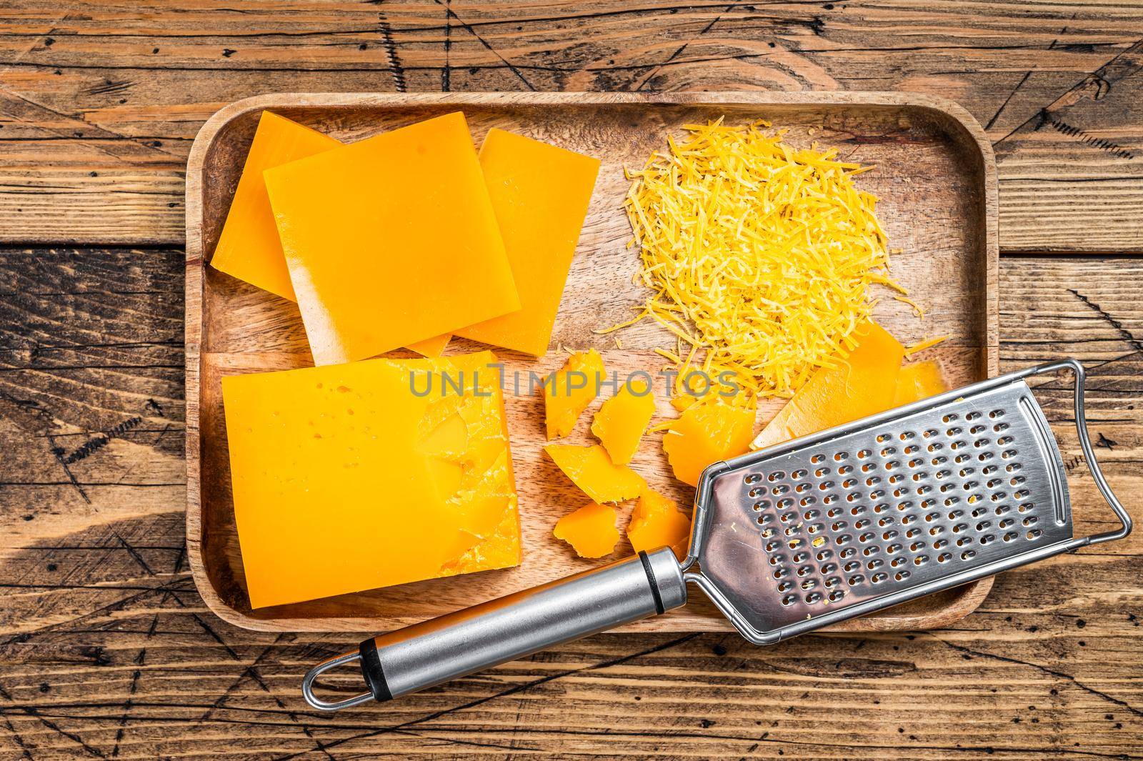 Cheddar Cheese Grated and diceded in a wooden tray. wooden background. Top view by Composter
