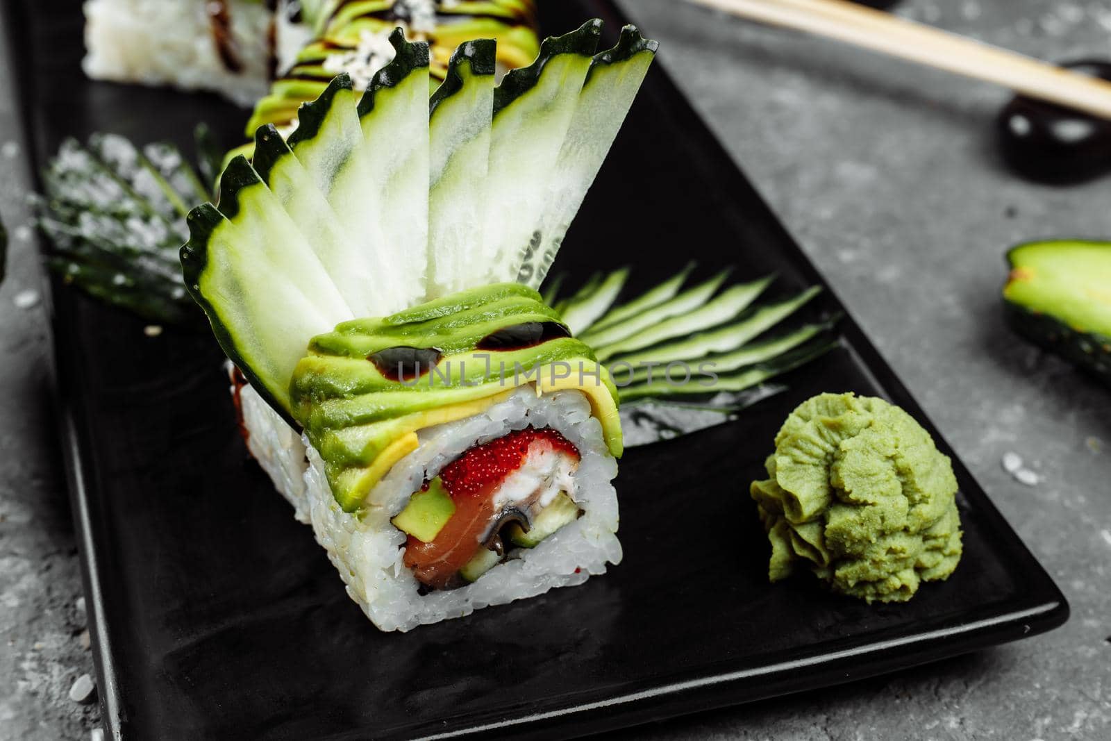 Green dragon sushi roll with eel, avocado, cucumber and ginger, accompanied with fried tempura shrimp. Traditional asian rice sushi healthy seafood.