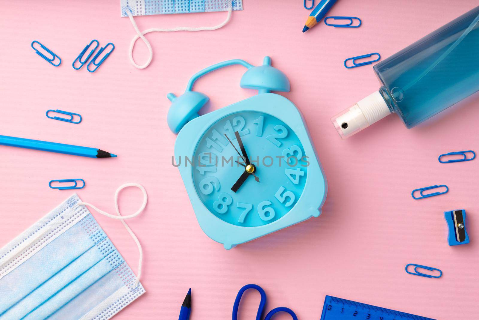 Blue alarm clock and medical face mask, top view