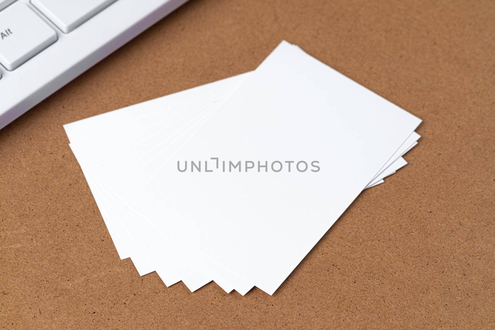 Blank business cards with supplies and keyboard on office table. Close up.