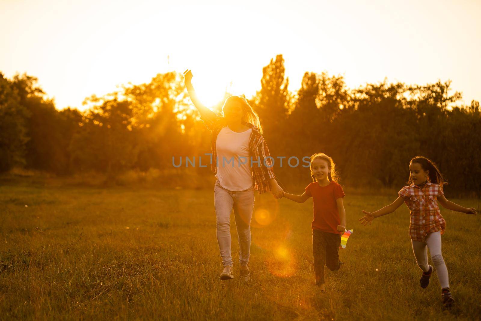 mothers and daughters in a field at sunset with an kite by Andelov13