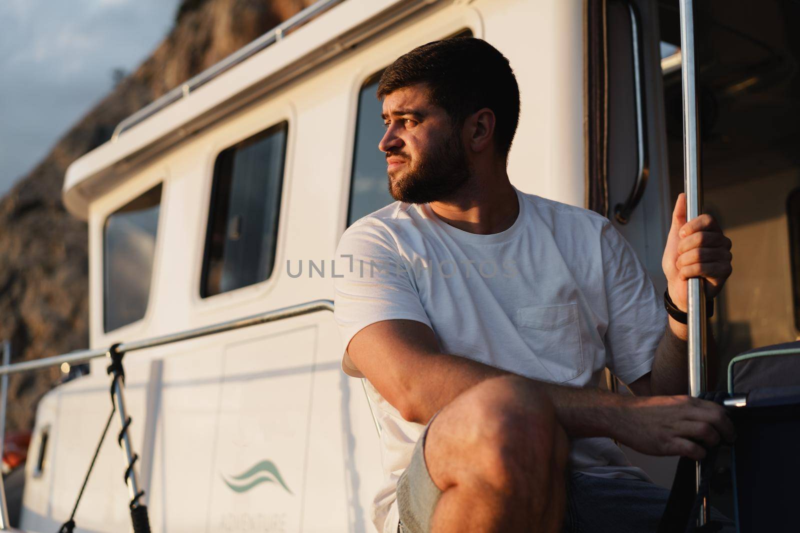 Portrait of a young caucasian bearded man sitting on a deck of sailboat, close up