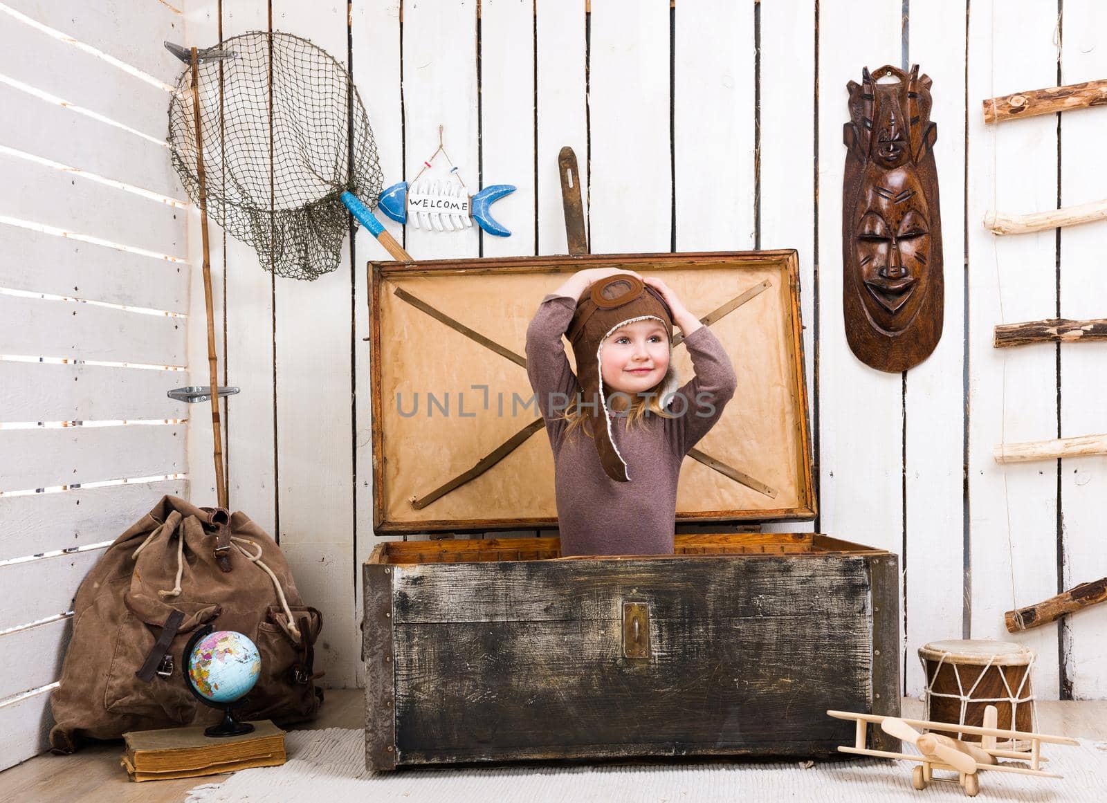 funny little girl-pilot in old wooden chest with hands up