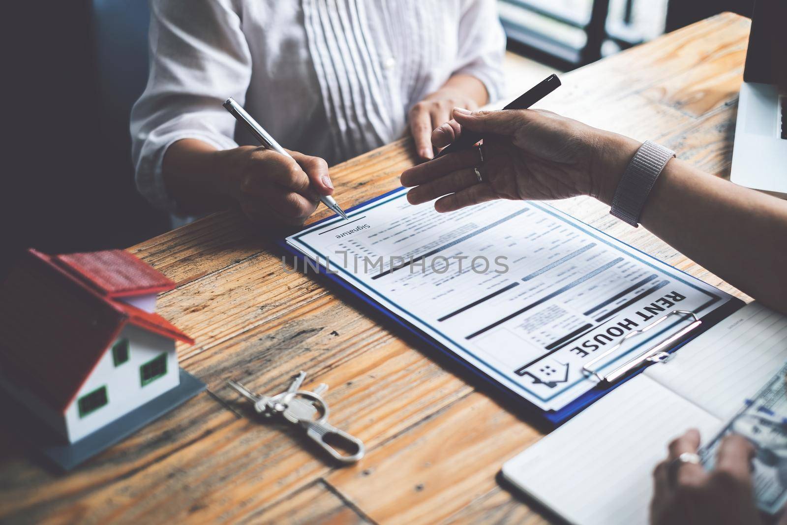 Close up of Business woman pointing and signing agreement for buying house. Bank manager and real estate concept.