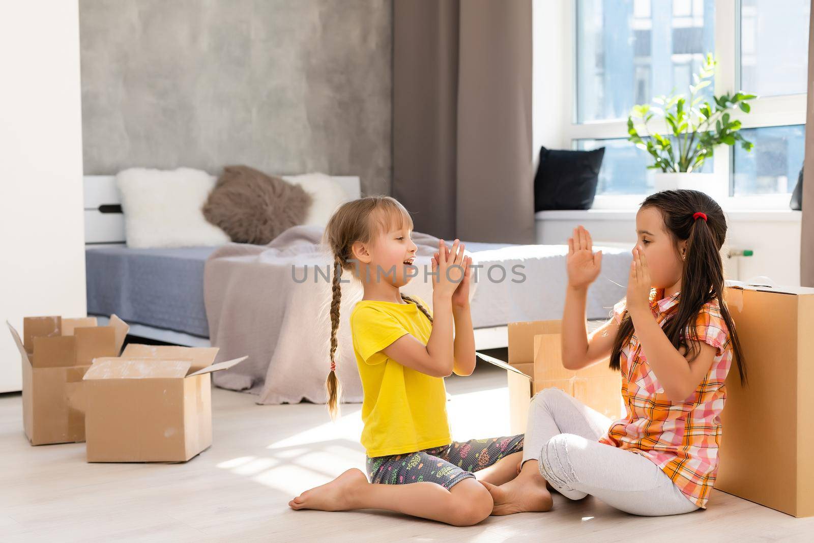 Excited funny kids girls running inside luxury big modern house on moving day, cute children entering exploring new home, happy young family buying real estate