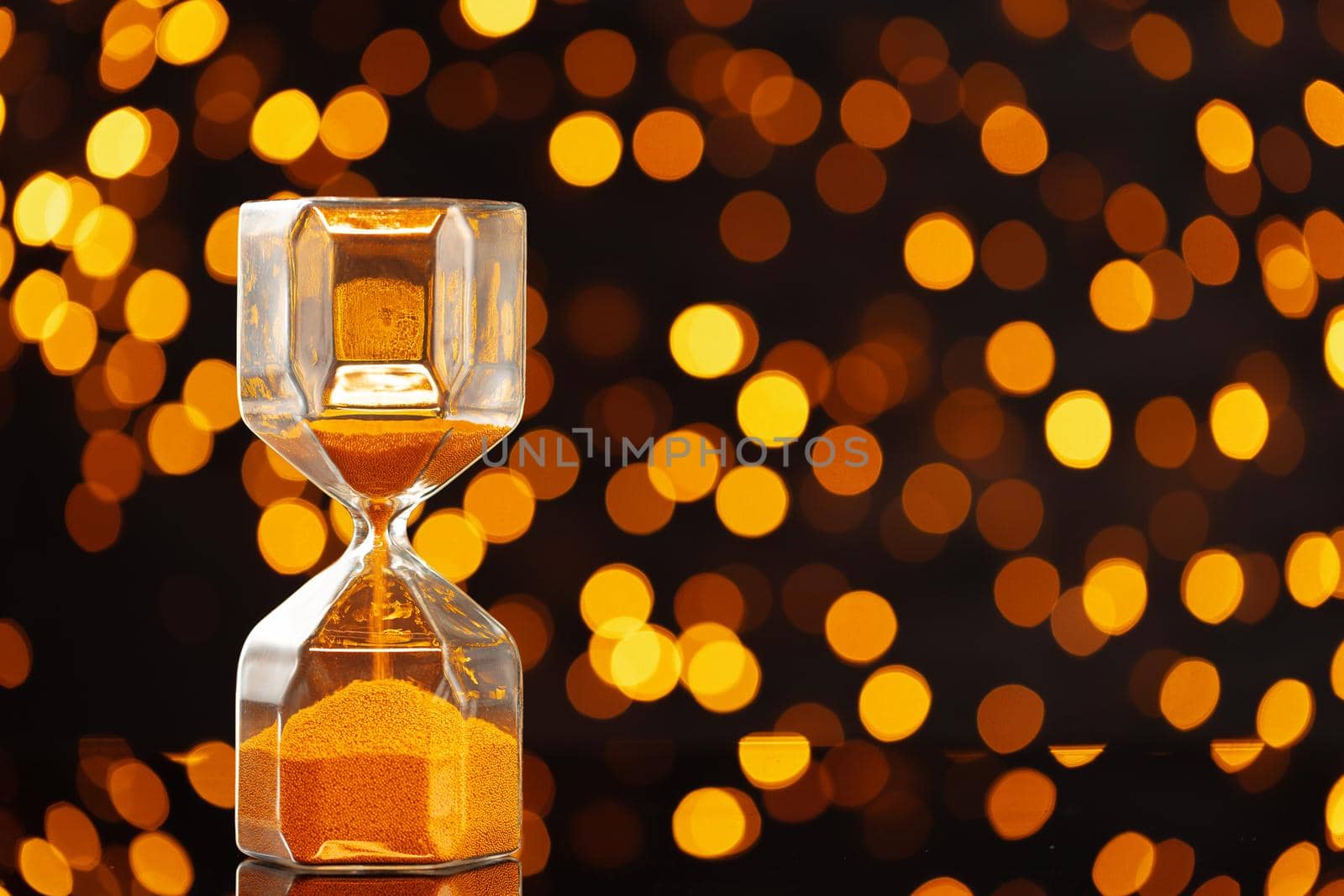 Golden hourglass against golden bokeh lights, Christmas background