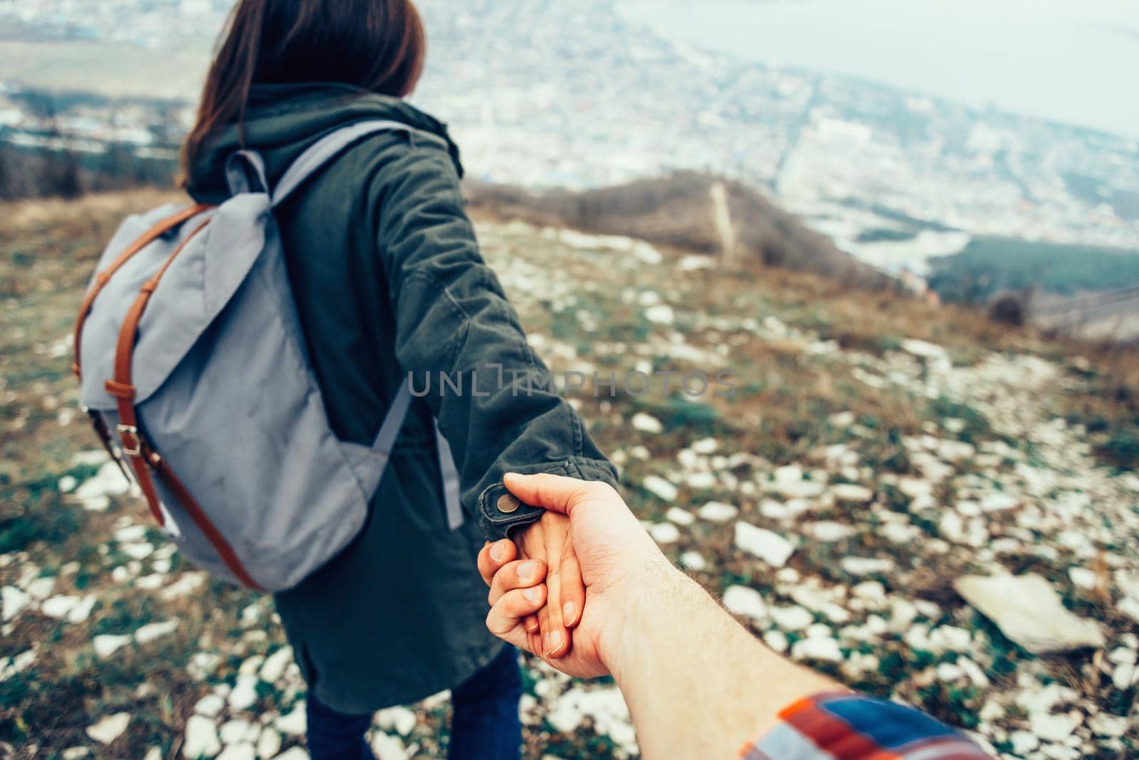 Hiker young woman holding man's hand and leading him on nature outdoor. Couple in love. Focus on hands. Image with instagram filter
