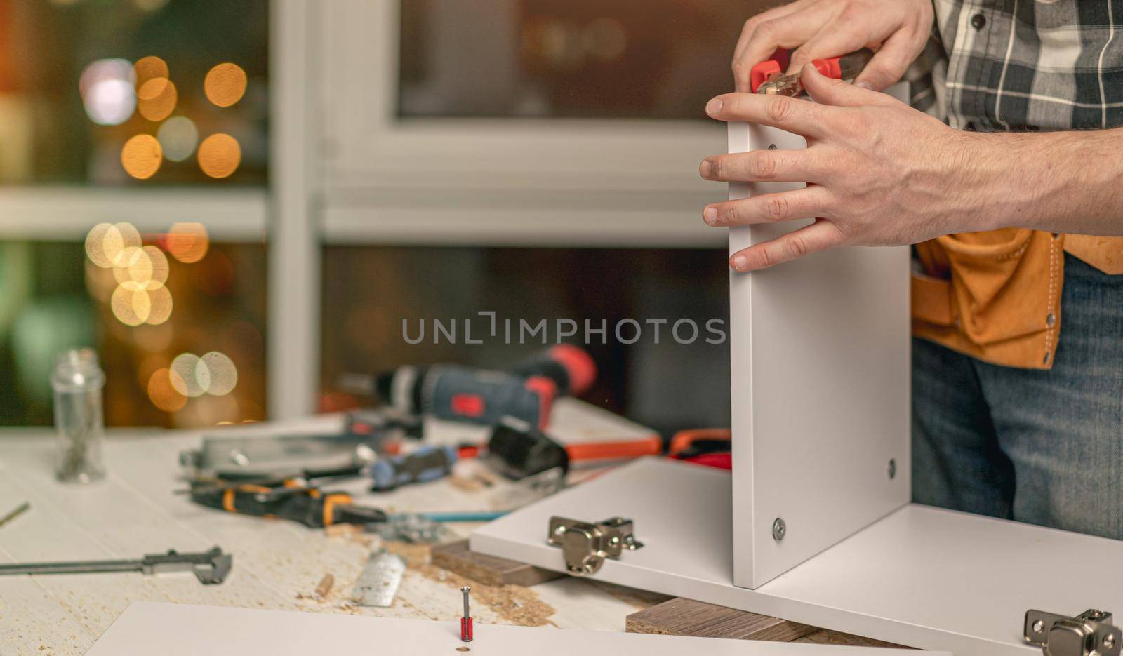 Man working using hammer for parts connection during process of wooden furniture manufacturing in workshop