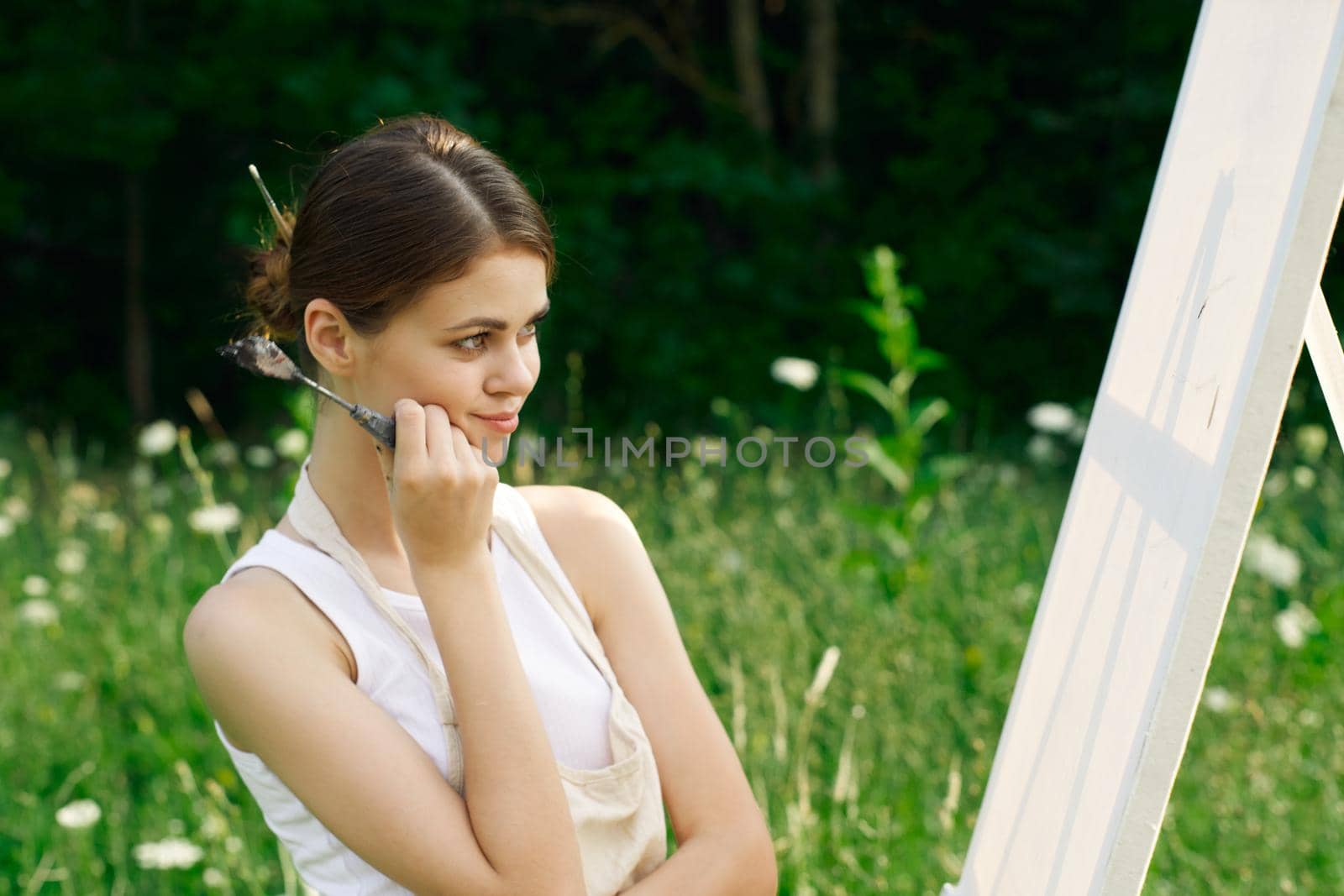 woman artist outdoors with palette of paints paints a picture by Vichizh