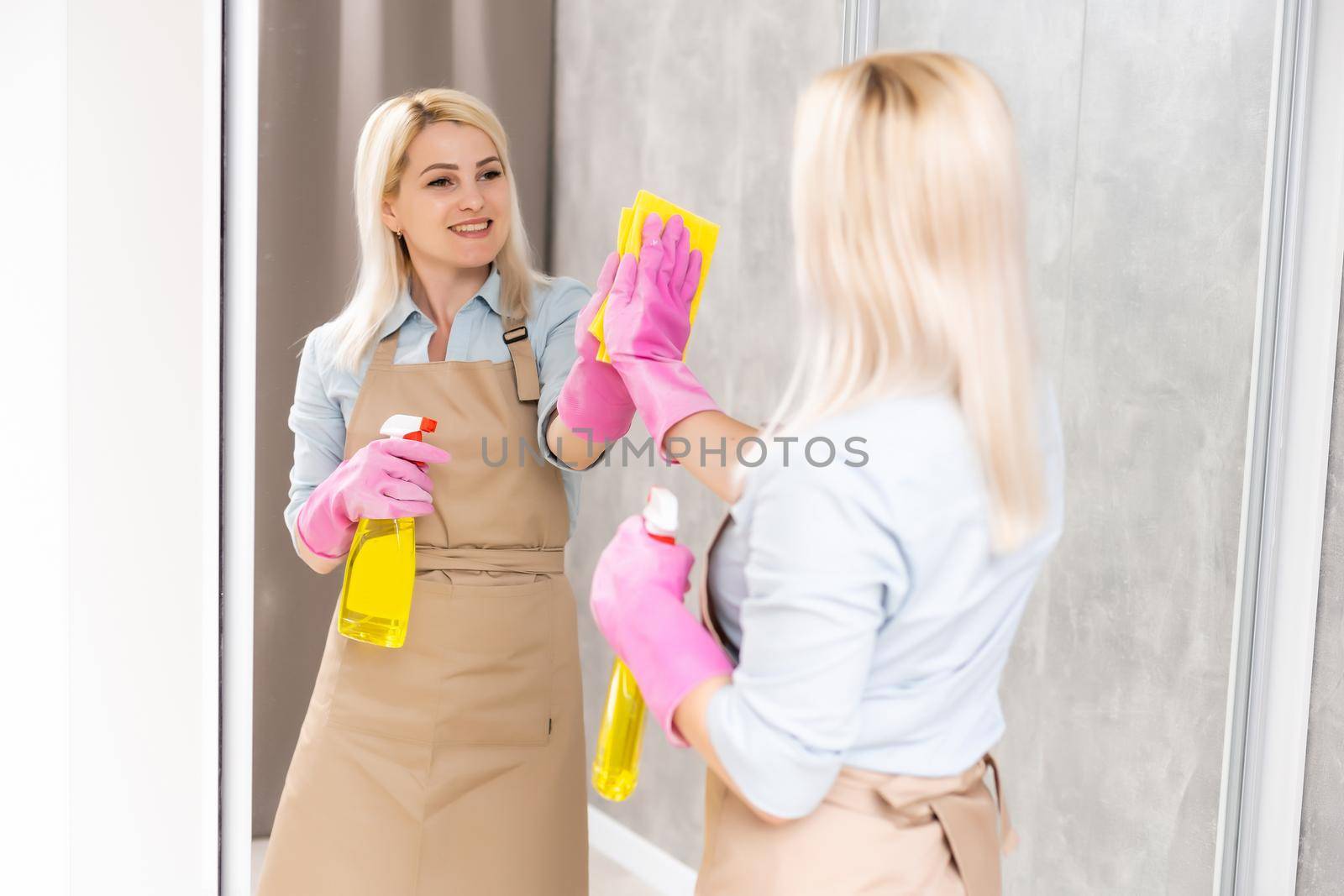 people, housework and housekeeping concept - close up of happy woman cleaning mirror with rag at home