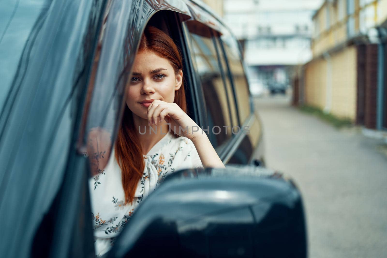 cheerful woman driving a car looks out of the window. High quality photo
