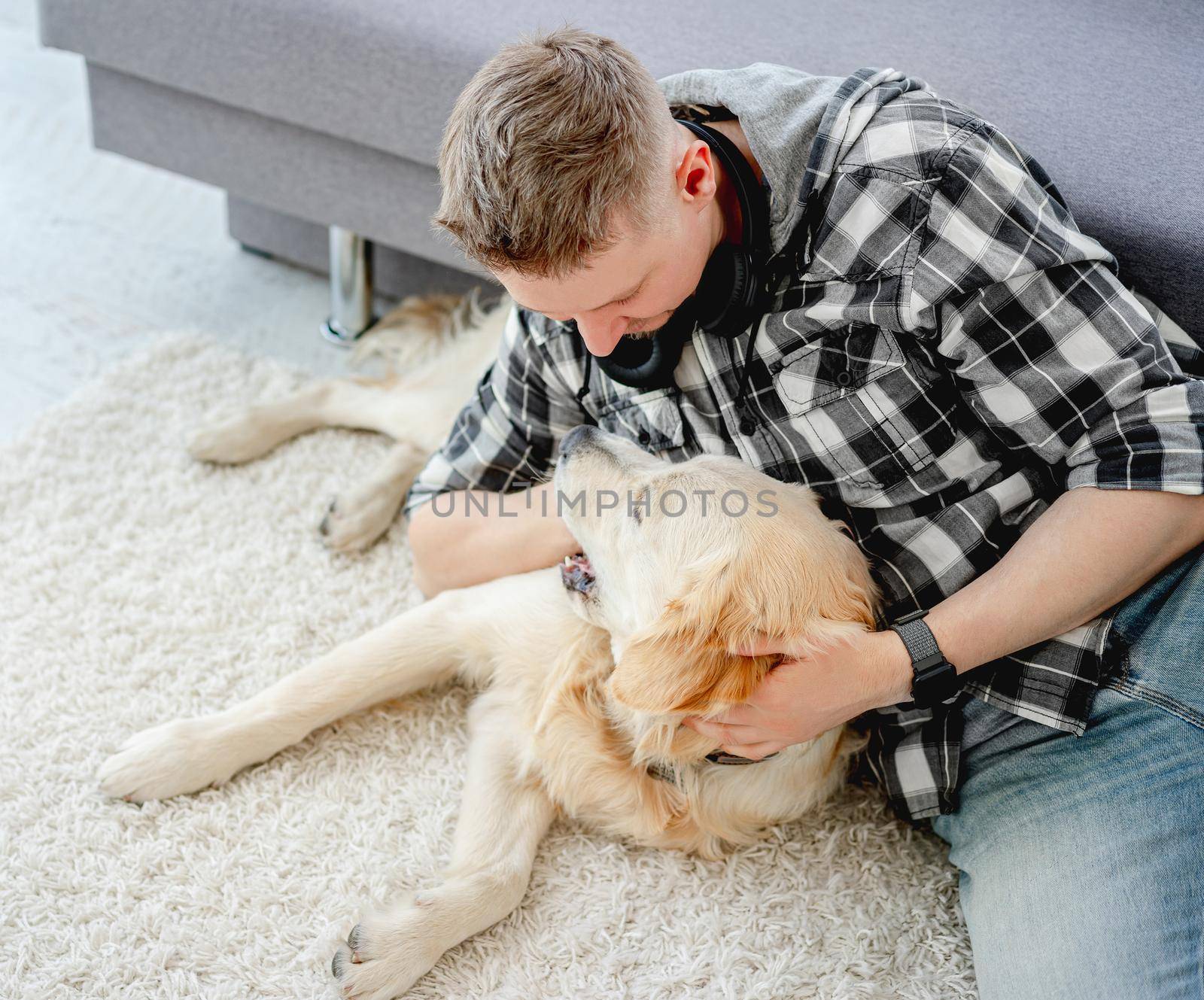 Handsome man with cute dog in light room