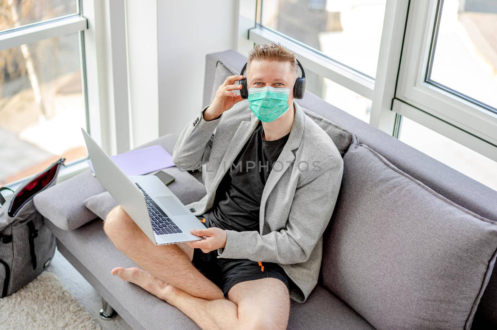 Man in medical mask working at home during covid pandemic