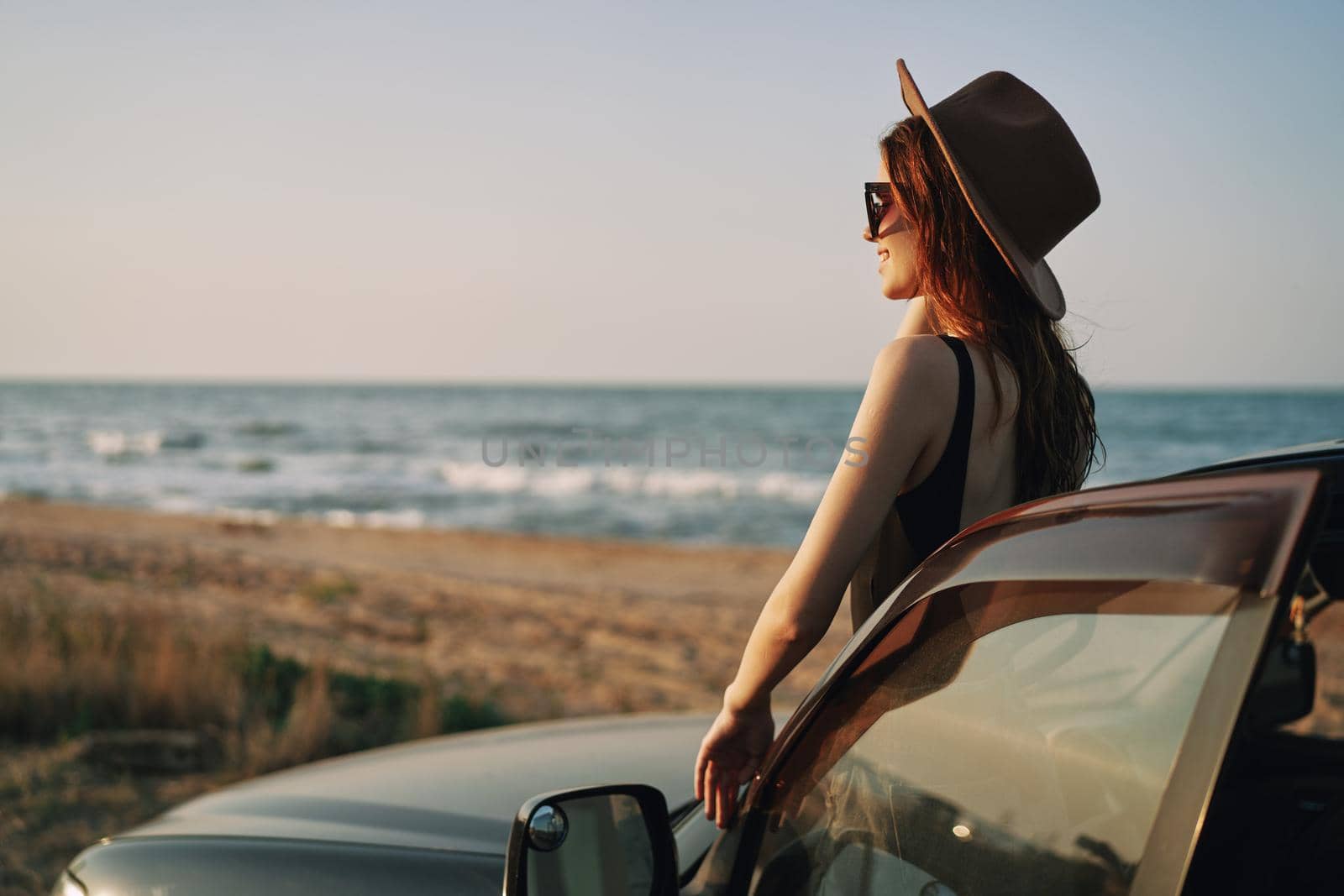 pretty woman in sunglasses near the car on the beach travel lifestyle. High quality photo