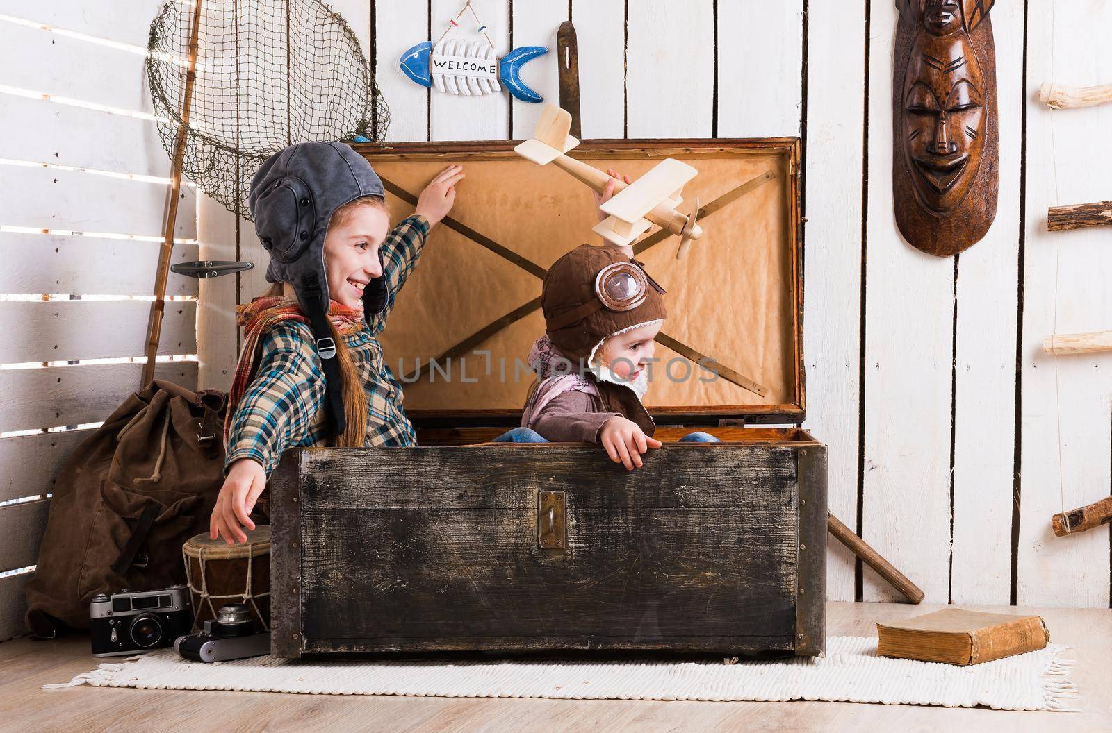 two playful little girls pretending pilots in old big wooden chest