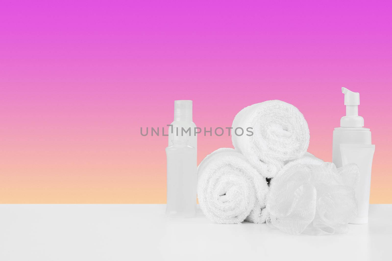 Pile of towels, bottles with shampoo on white table isolated