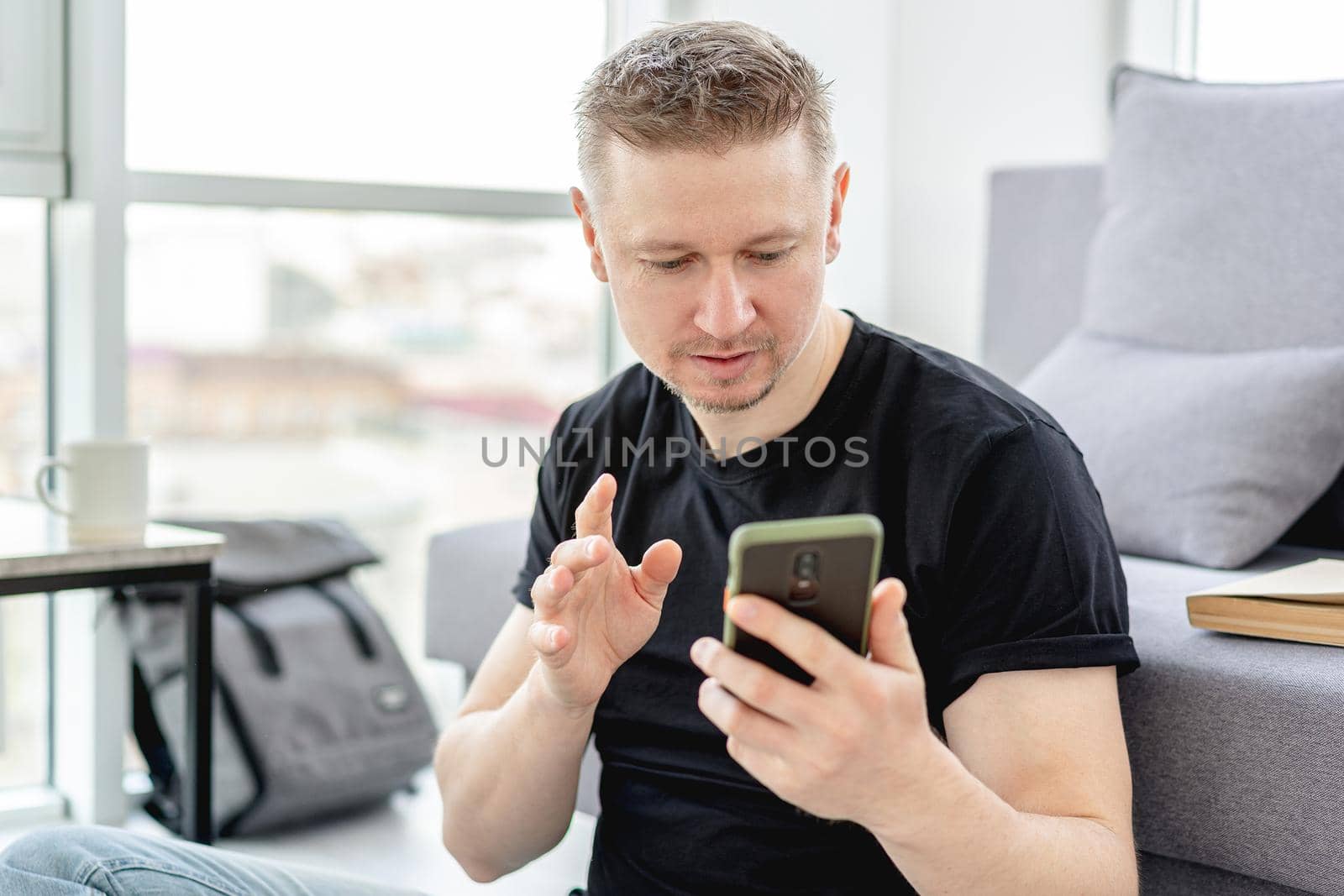 Smiling man looking into smart phone indoors