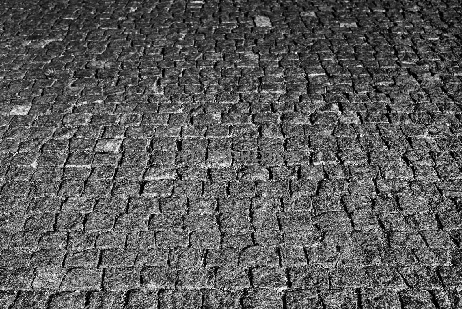 Stone road close up. Old pavement of granite. Grey square cobblestone sidewalk. Mock up or vintage grunge texture.