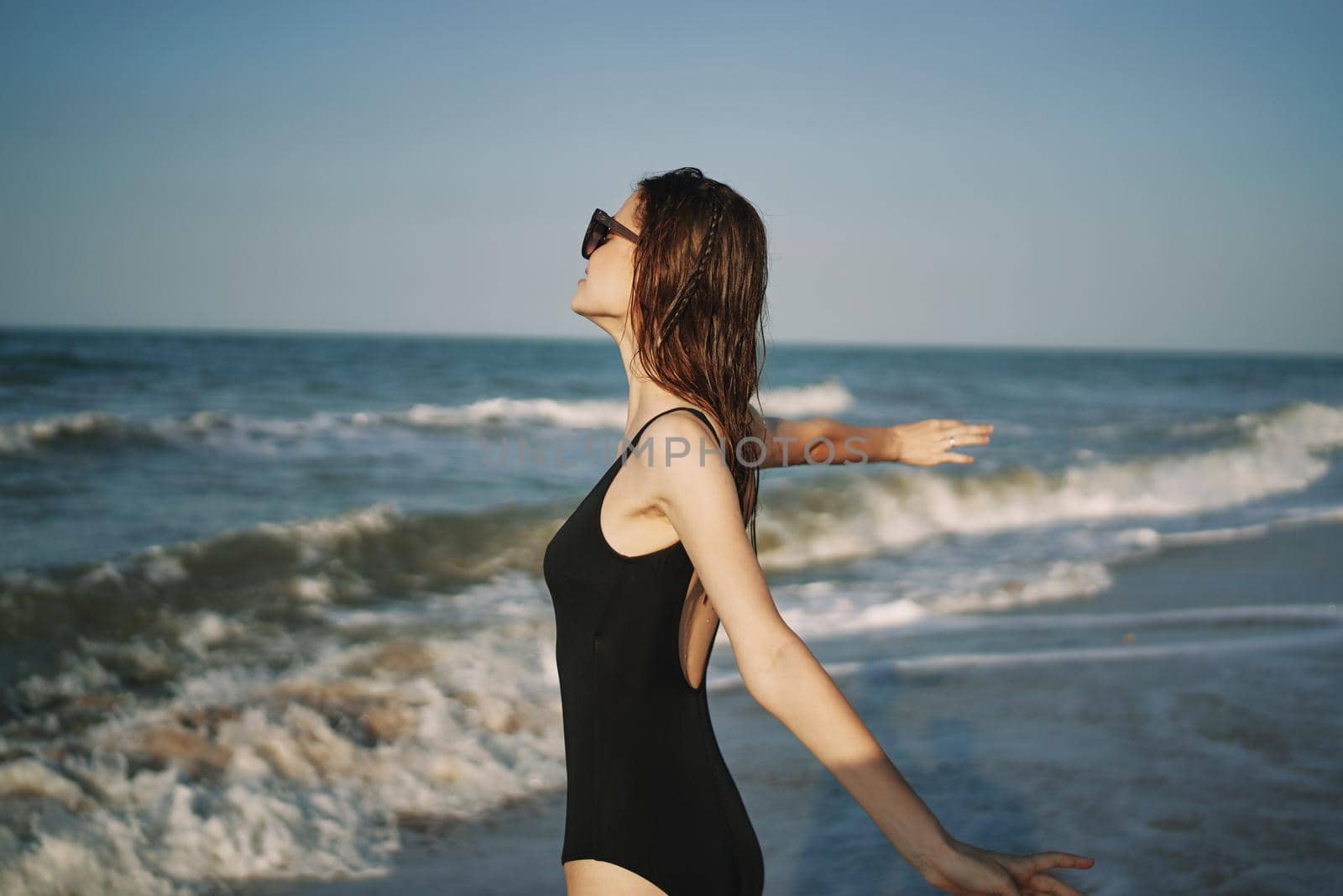 pretty woman in black swimsuit posing sun walking on the beach. High quality photo