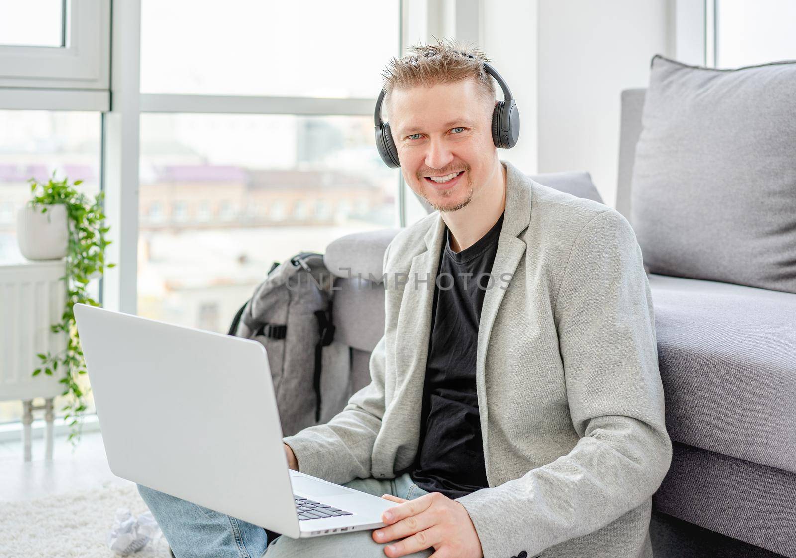 Happy man working on laptop in light apartment