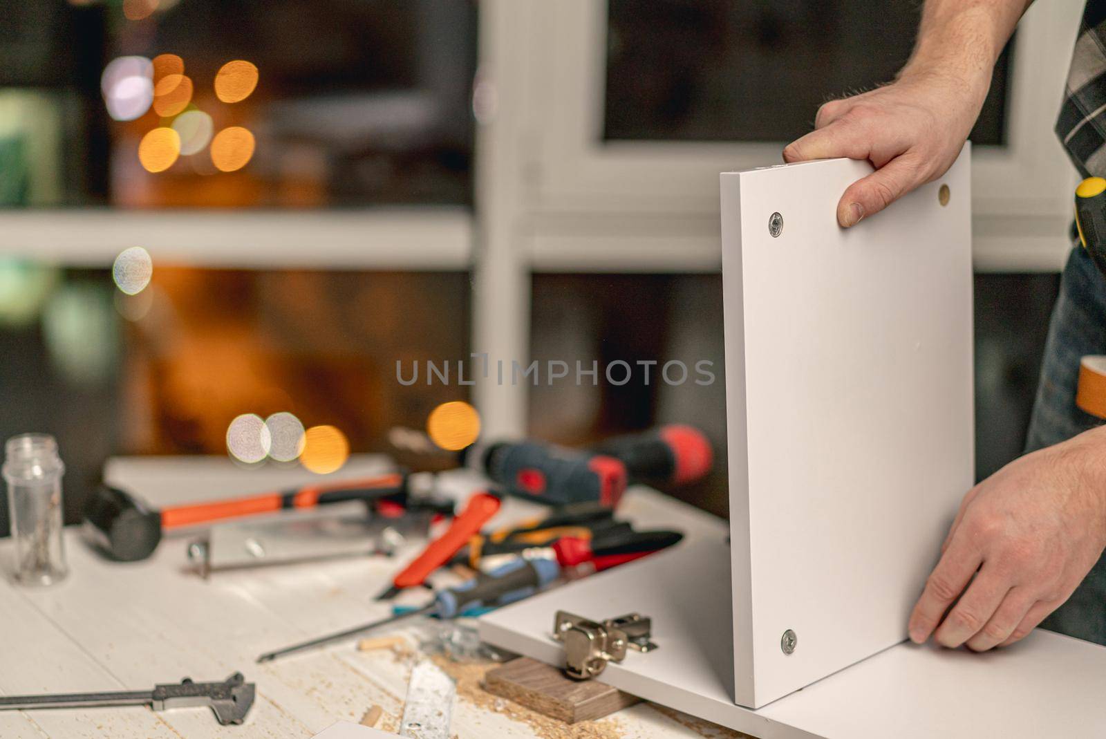 Man working connecting board of shelf during process of wooden furniture manufacturing in workshop