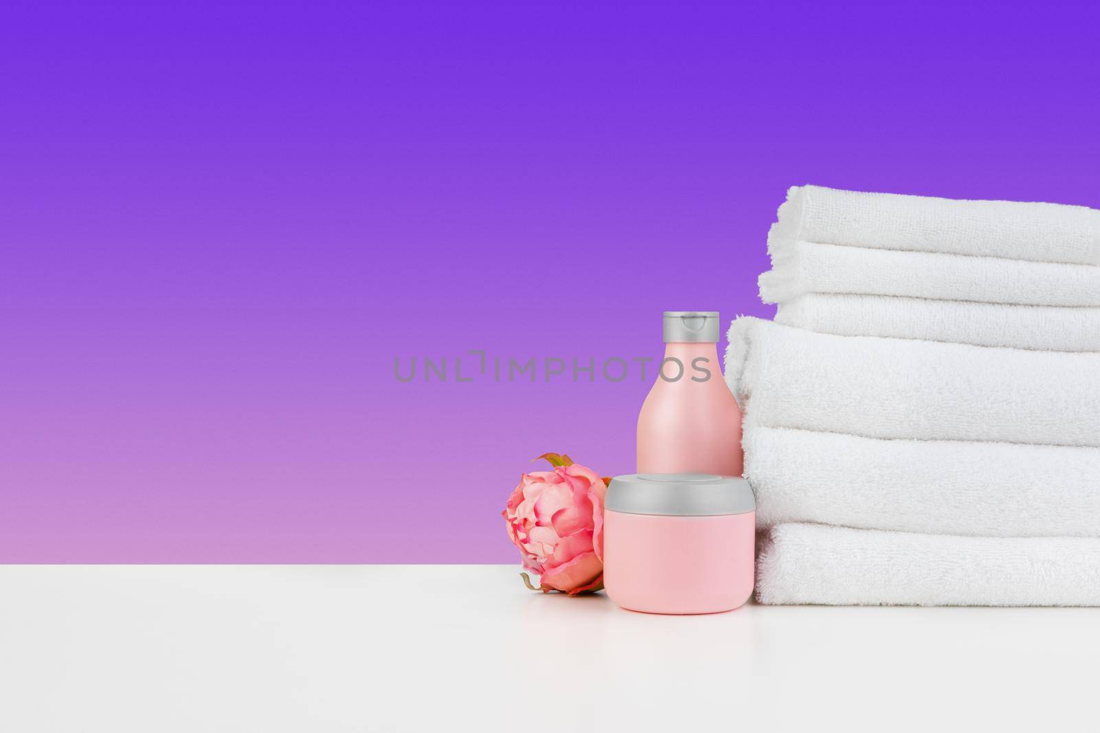 Stacked clean towels on white table against color background, front view