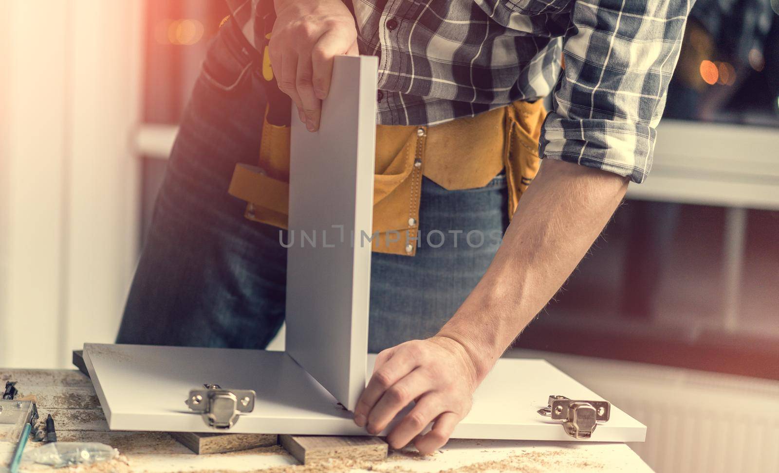 Man working using hammer for parts connection during process of wooden furniture manufacturing in workshop