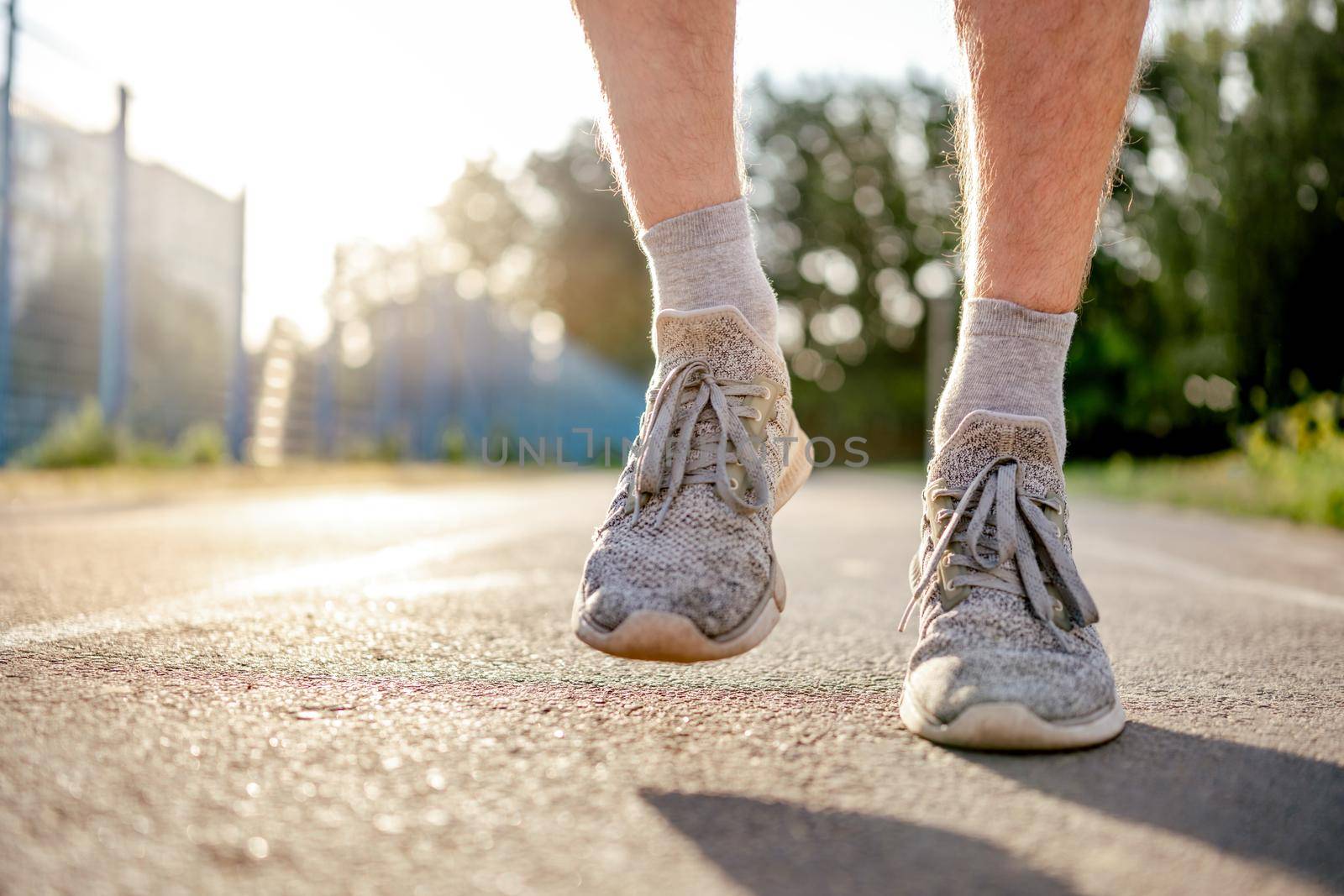 Closeup view of man guy legs feet wearing sport sneakers during running at the stadium outdoors. Male person during workout. Sportsman exercising in summertime