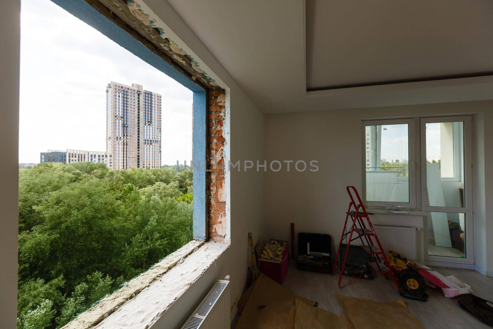 Empty frame on a wide panoramic window. Gorgeous view from the window of an apartment in a multi-storey building. Roofs of houses and trees from a height. Beautiful view through the window. Frame for